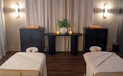 A serene, dimly lit spa room features two massage tables