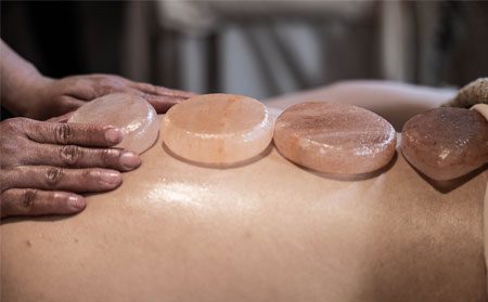 Image of Himalayan salt stones being placed on a client's back.	