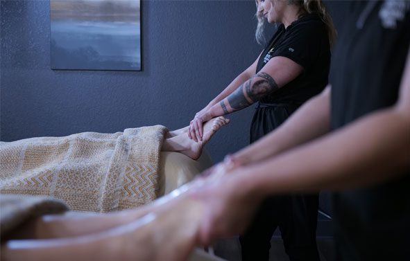 A therapist performing a foot massage during a couple's treatment.
