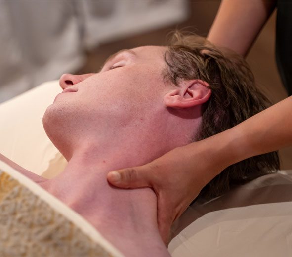 A man receiving a massage on his neck by a therapist