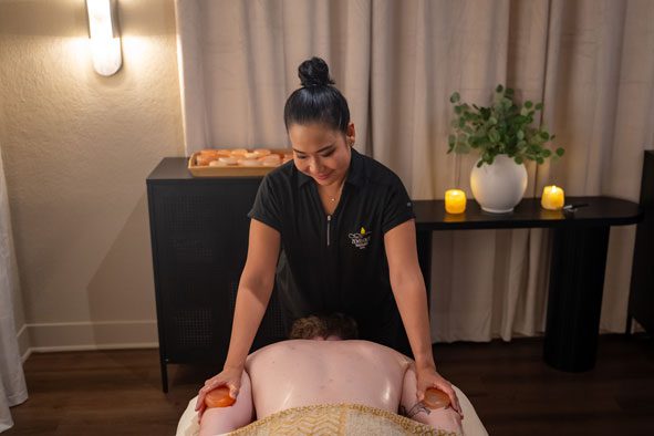 A man receiving a hot stone massage by a therapist