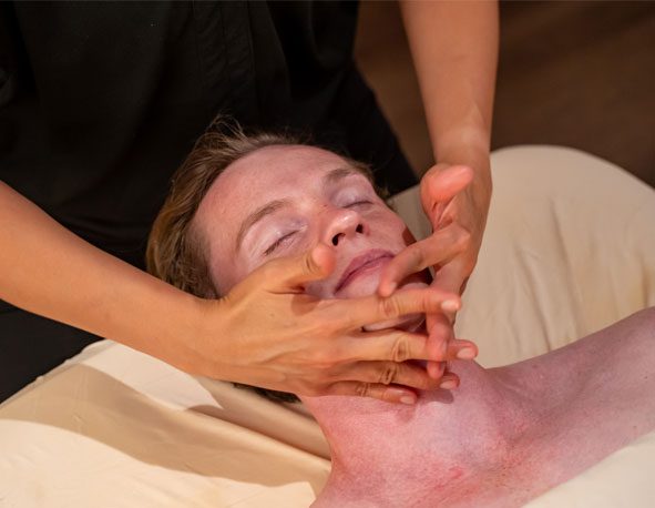 A man receiving a massage on his face by a therapist