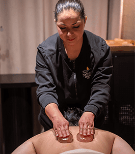 A therapist perfoming a heart stone massage on a client.