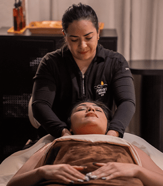 A woman relaxing while receiving a single massage hot stone treatment on her back.	