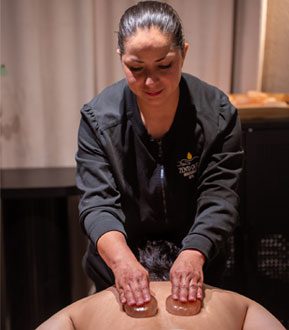 hot stone treat A therapist perfoming a hot stone massage on a man.